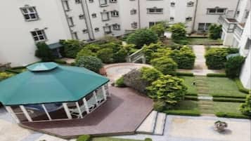 Um pátio com um gazebo, gramados bem cuidados e um edifício com várias janelas e sacadas.