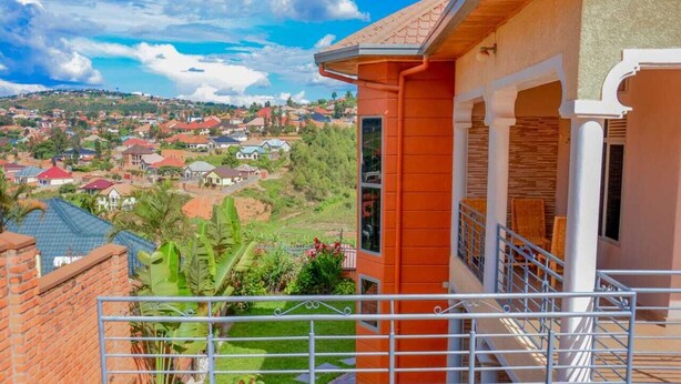 A residential building with a balcony, a view of a residential area, and a garden. - mountain view apartment (Kigali)