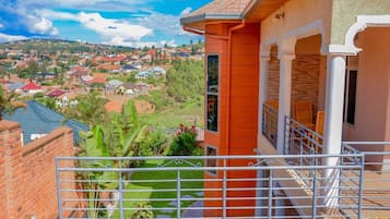 A residential building with a balcony, a view of a residential area, and a garden.