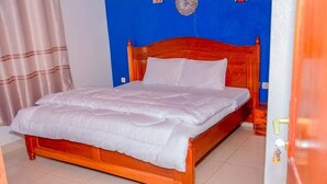 A single bed with a wooden headboard in a room with blue walls. - mountain view apartment (Kigali)