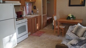 Una cocina compacta con armarios de madera, un horno blanco y una zona de comedor con mesa y sillas.