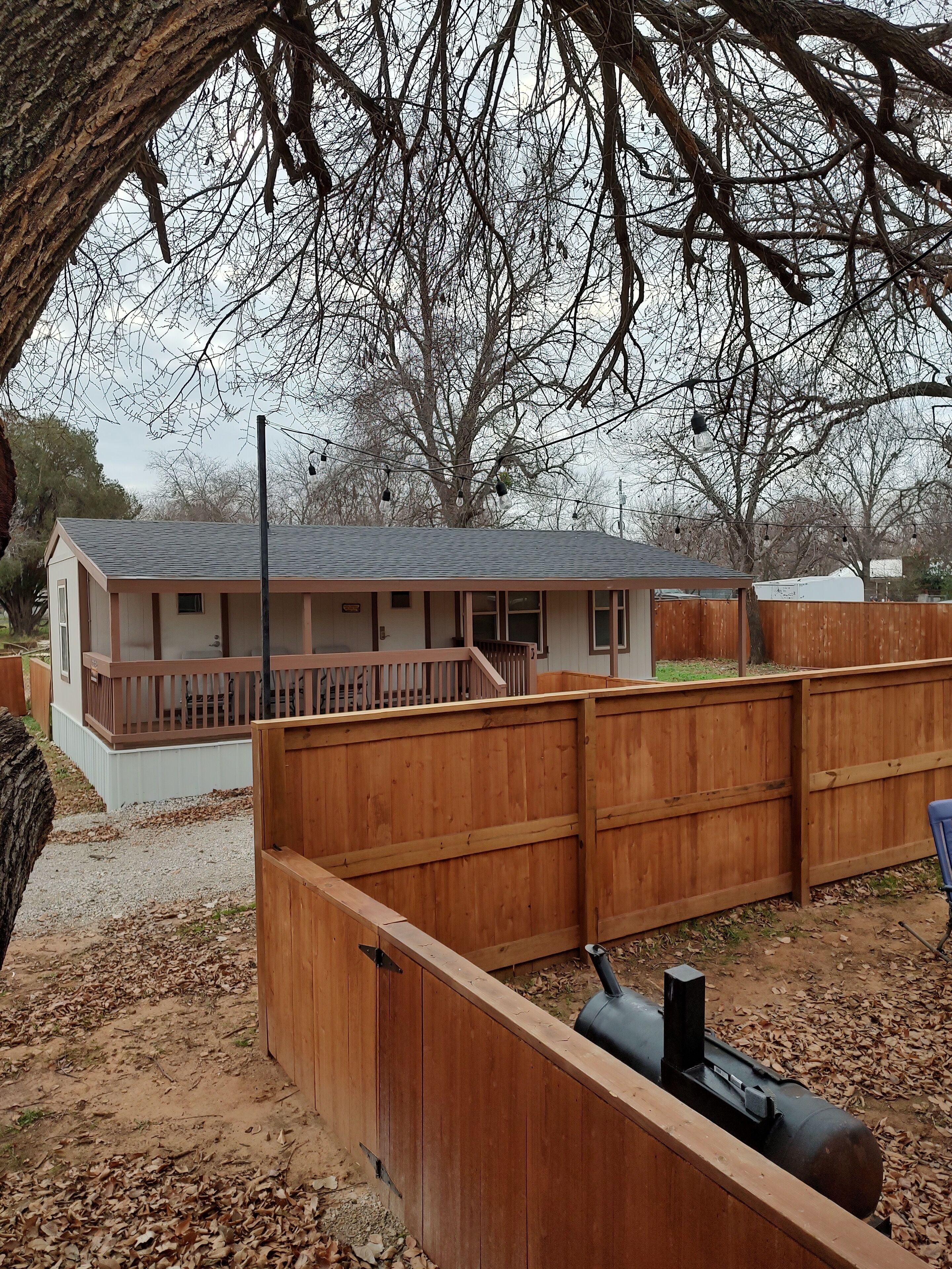 A single-story house with a fenced backyard, a visible chimney, and a small deck area.