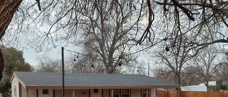 A single-story house with a fenced backyard, a visible chimney, and a small deck area.