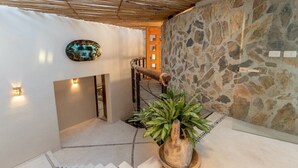 Una escalera con pared de piedra, techo de madera y una planta en maceta.