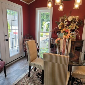 A dining area with striped chairs, a glass table, and a floral centerpiece. - Renovated Turn Of The Century Farmhouse with three bedrooms (Rockport)