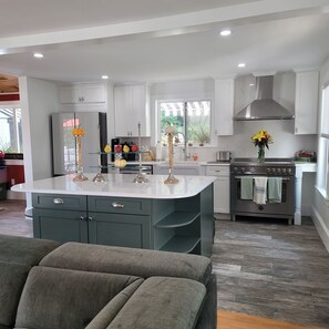 A modern kitchen with white cabinets, a central island, and a built-in oven.