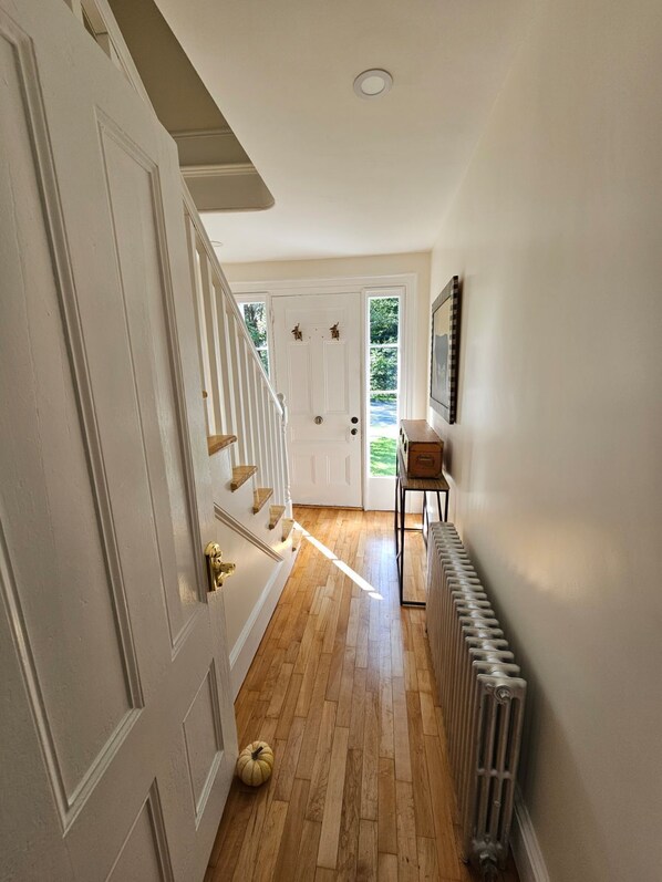 A hallway with a wooden floor, white walls, and a radiator.