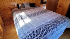 A wooden cabin bedroom with a bed, pillows, and a window. - Private Cabin with access to Rust Pond Ferris (Wolfeboro)