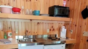 A compact kitchen with wooden walls, a stainless steel sink, a microwave, and a refrigerator. - Private Cabin with access to Rust Pond Ferris (Wolfeboro)