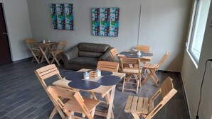 A room with a sofa, wooden tables, and chairs arranged for dining. - Yolotl Sleep Experience (Piedras Negras)