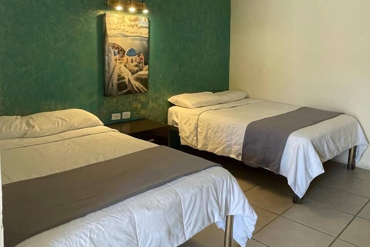 A room with two single beds, a green accent wall, and a painting.