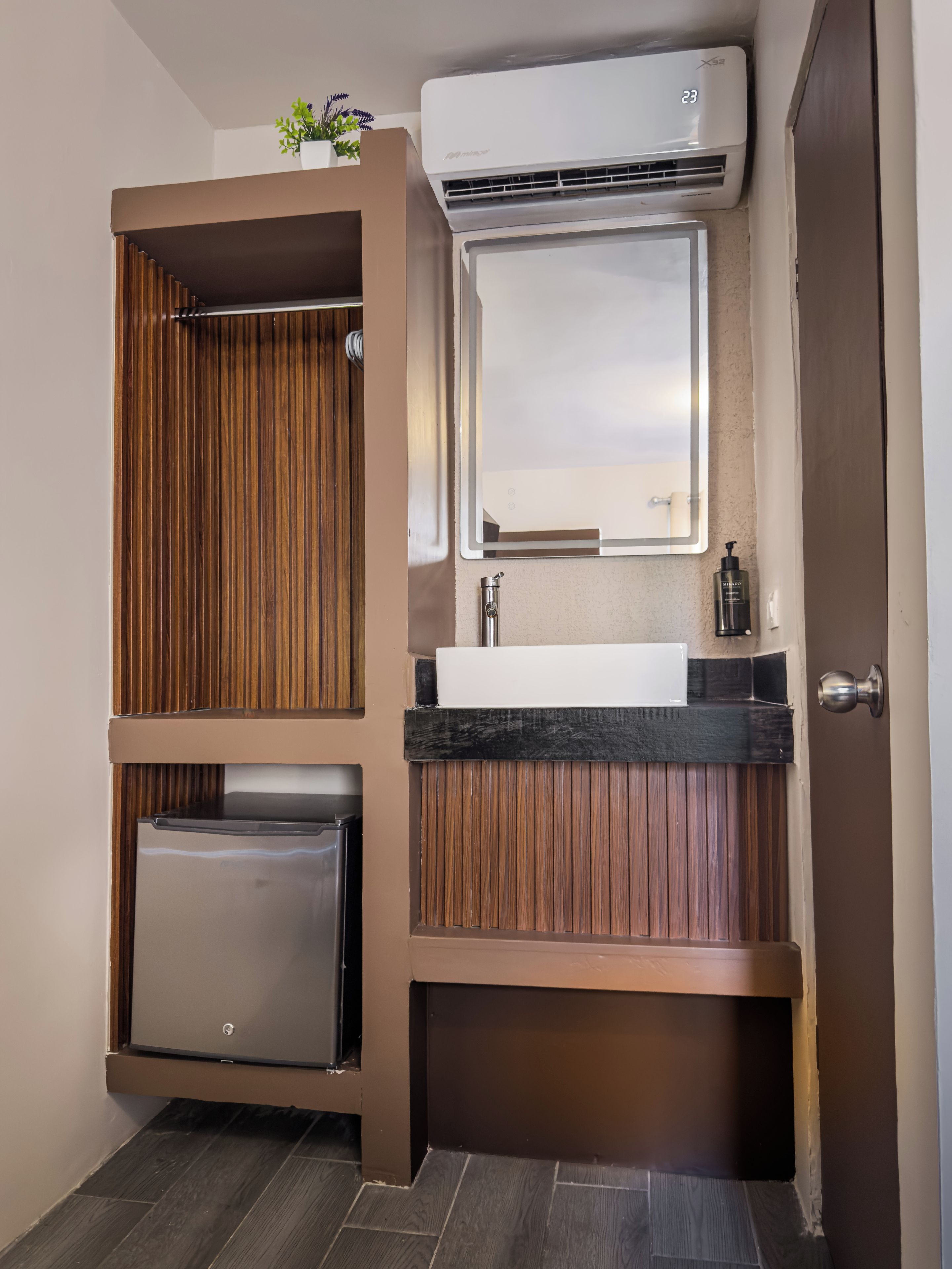 Une salle de bain compacte avec un lavabo intégré, un miroir et un petit réfrigérateur.