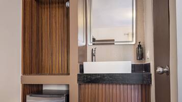 Une salle de bain compacte avec un lavabo intégré, un miroir et un petit réfrigérateur.