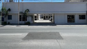 A building with a covered entrance, a parking lot, and a clear sky. - Yolotl Sleep Experience (Piedras Negras)