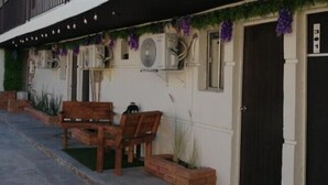 A building with a black door, air conditioning units, and a bench outside. - Yolotl Sleep Experience (Piedras Negras)