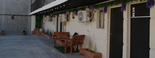 A building with a black door, air conditioning units, and a bench outside. - Yolotl Sleep Experience (Piedras Negras)