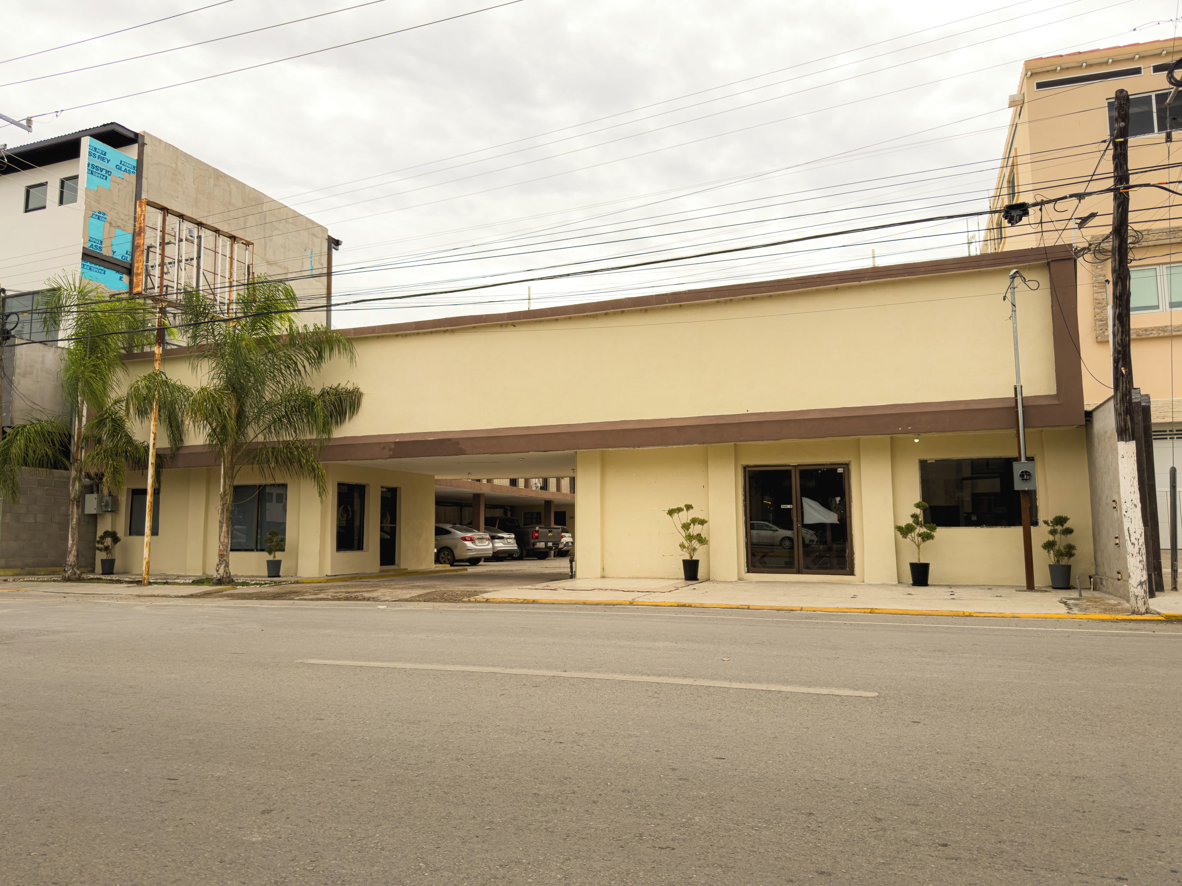 A building with a flat roof, multiple windows, and a parking area in front.