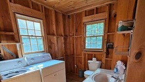 Une petite salle de bain en bois, comprenant une machine à laver, des toilettes et un lavabo.