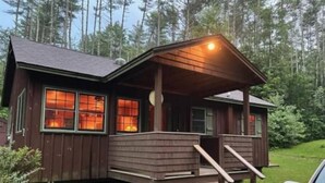 Une cabane dotée d’un porche, d’une façade en bois et d’un petit escalier menant à l’entrée.