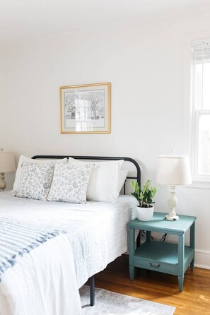 A bedroom with a bed, bedside table, lamp, and a framed picture on the wall. - Walk to Marietta Square -The Cottage on Maple (Marietta)