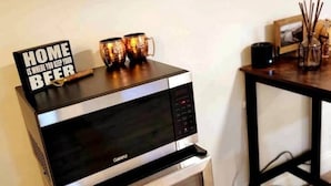A microwave on a small table with a sign that reads "HOME IS WHERE YOU KEEP YOUR BEER." - Charming Modern Farmhouse Suite (Kenilworth)
