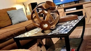 A living room with a brown sofa, a coffee table with a decorative item, and a flat-screen TV on a stand. - Charming Modern Farmhouse Suite (Kenilworth)