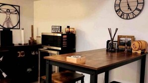 A modern living room with a wooden table, a black TV stand, and a large wall clock. - Charming Modern Farmhouse Suite (Kenilworth)