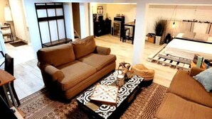 A modern living room with a brown sofa, a patterned coffee table, and a dining area with a table and chairs. - Charming Modern Farmhouse Suite (Kenilworth)