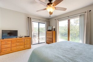 A bedroom with a bed, a ceiling fan, a dresser, a television, and a sliding glass door leading to a balcony. - Walk to Pool + Lake: Cozy Osage Beach Condo (Osage Beach)