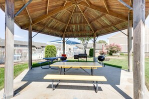 A covered picnic area with a table and benches, surrounded by a fence and houses. - Walk to Pool + Lake: Cozy Osage Beach Condo (Osage Beach)
