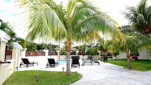 A pool area with lounge chairs and palm trees.