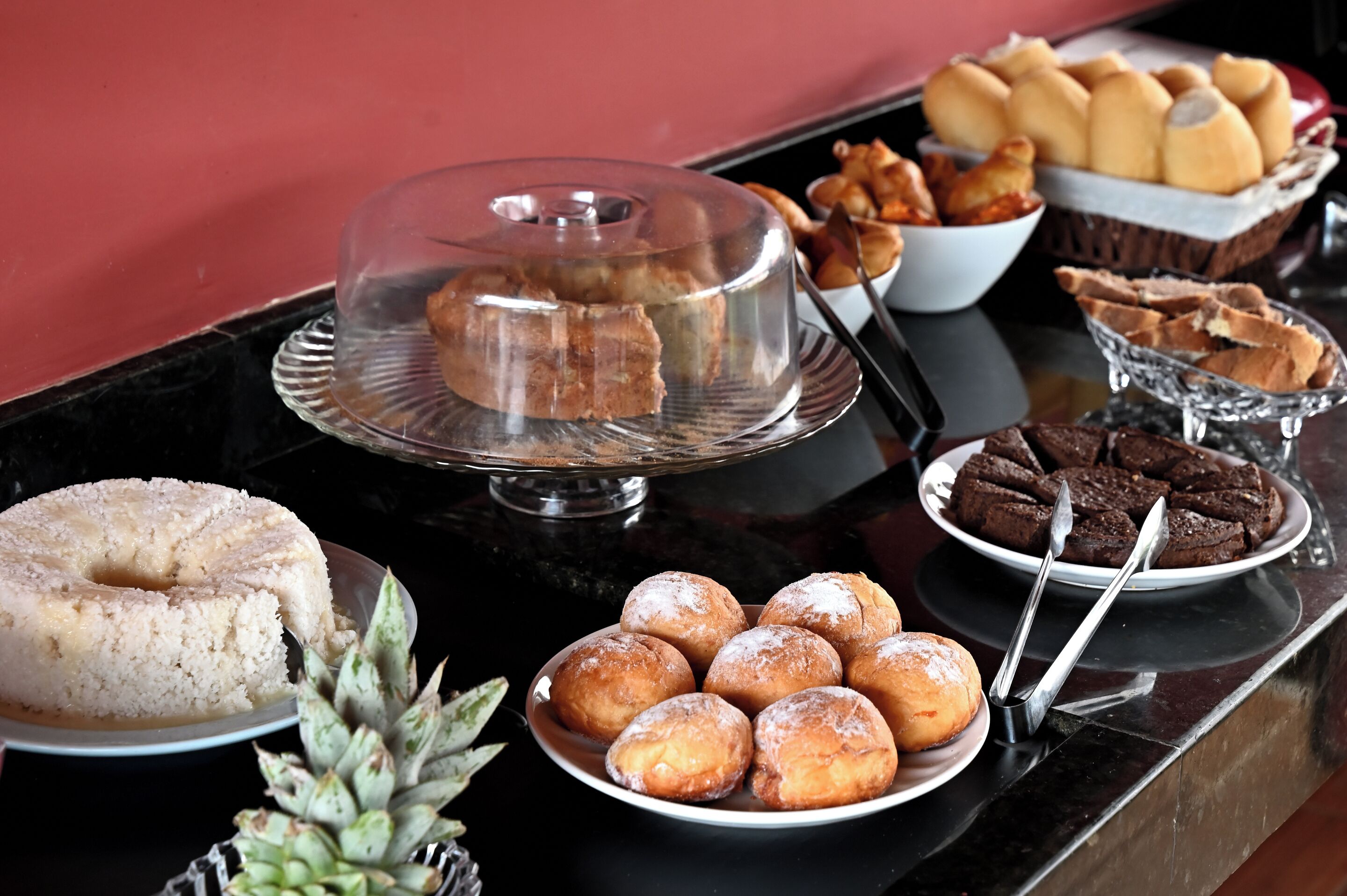 Une table de buffet proposant divers produits de boulangerie, notamment un gâteau recouvert de glaçage, des beignets et des pâtisseries.