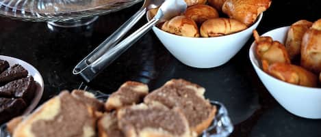 A buffet table with various baked goods including bread and pastries.