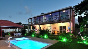 Ein zweistöckiges Haus mit Swimmingpool und Sitzgelegenheit im Freien.