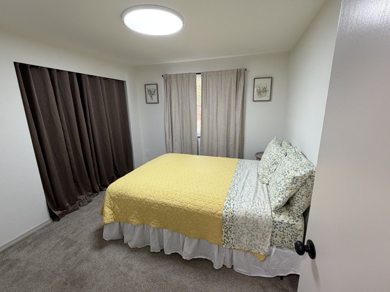 Ein Schlafzimmer mit Bett, Vorhängen, einem Fenster und einer Tür.