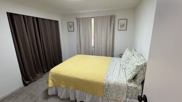 Ein Schlafzimmer mit Bett, Vorhängen, einem Fenster und einer Tür.