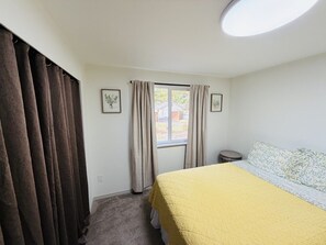 Une chambre à coucher avec un lit, une fenêtre avec des rideaux, une lucarne ronde et une petite table ronde.