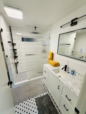 Un baño moderno con ducha, lavamanos y espejo.