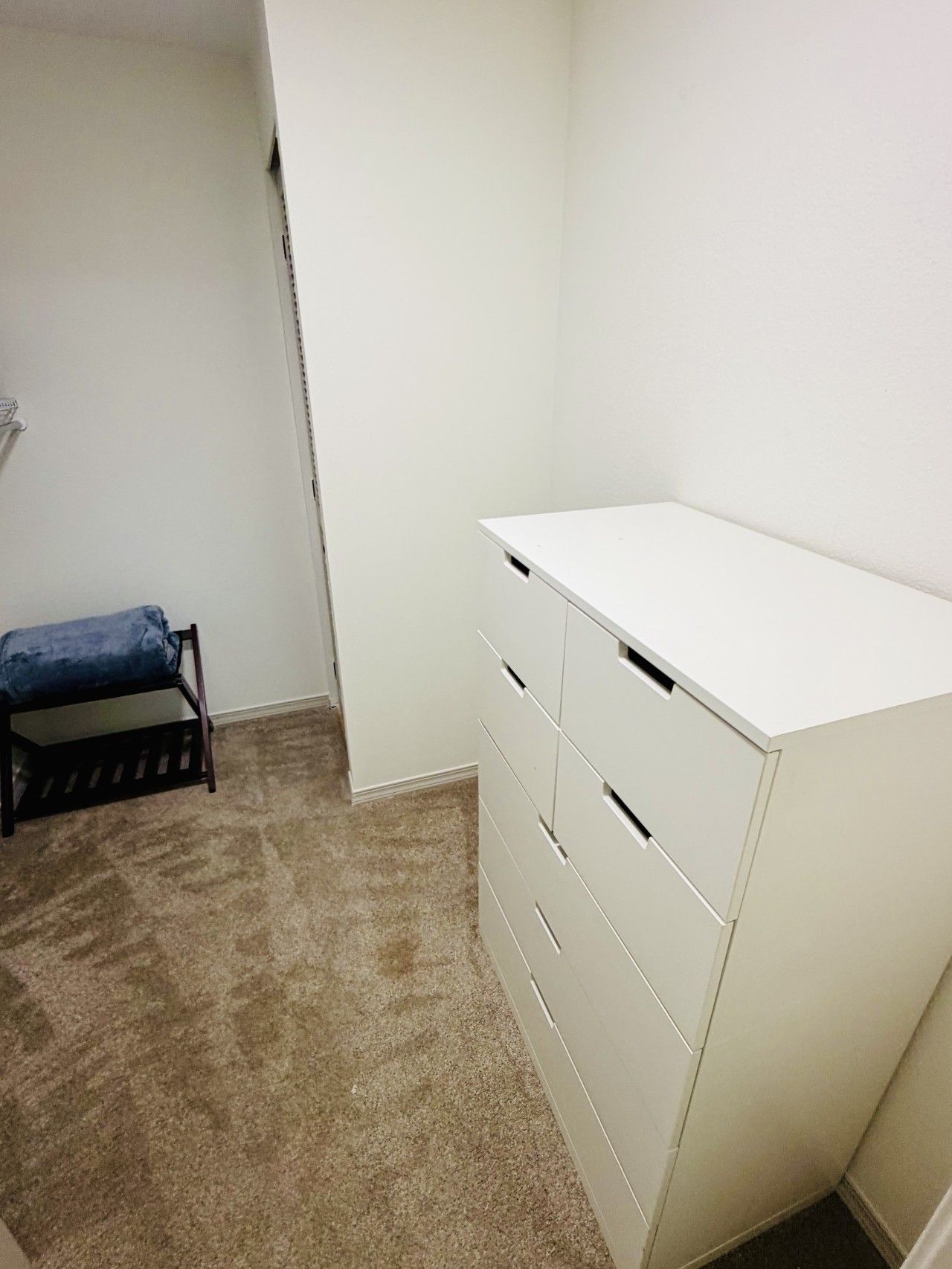 A room with a white desk, a chair, and a carpeted floor.