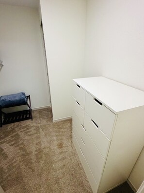 Une pièce avec un bureau blanc, une chaise et un sol recouvert d’une moquette.