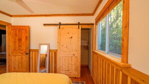 Une chambre à coucher avec un lit, une porte coulissante, une fenêtre et un ventilateur de plafond.