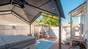 Un patio abrité avec un jacuzzi, un barbecue et une table de billard.