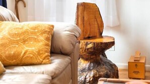 Een woonkamer met een bank, een houten kruk en een glazen tafel met een vaas.