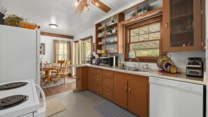 A kitchen with wooden cabinets, a white stove, a microwave, and a dishwasher.