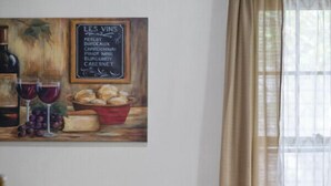 A dining area with a wooden table, six chairs, a floral centerpiece, and a chalkboard menu listing wine varieties.