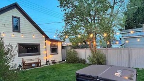 Ein Garten mit Whirlpool, einer Holzbank und Lichterketten.