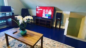 Ein Wohnzimmer mit Fernseher, Couchtisch aus Holz und einem floralen Teppich.