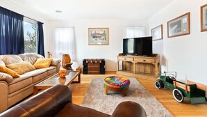 Ein Wohnzimmer mit einer Couch, einem Couchtisch, einem Hocker, einem Fernseher und einem Spielzeugauto.