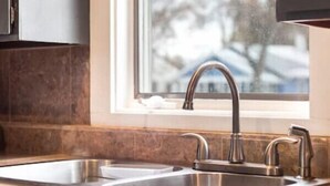 Eine Küche mit zwei Edelstahl-Spülen, einem Fenster und Schränken.