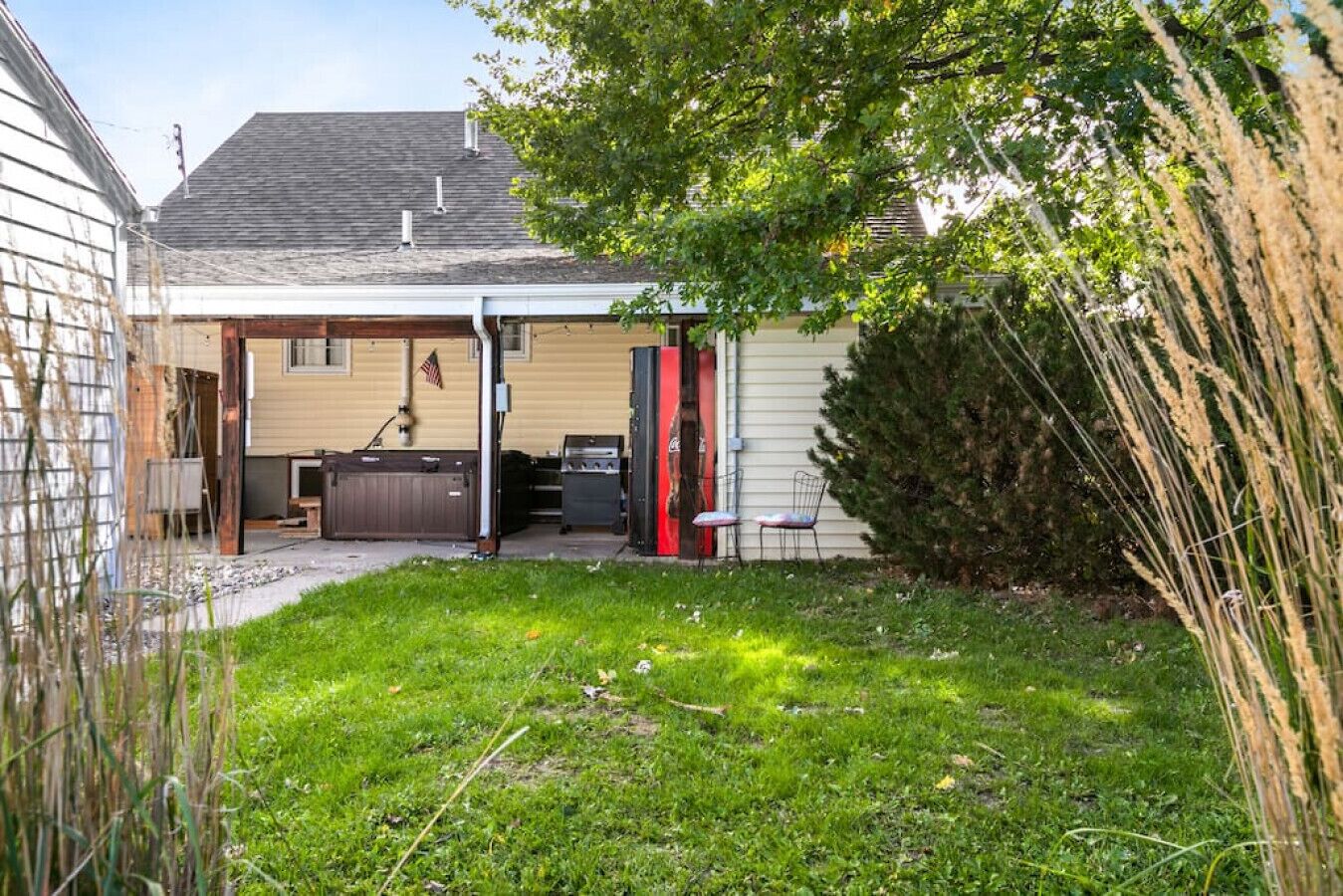 A residential backyard with a covered patio, a barbecue grill, and a shed.